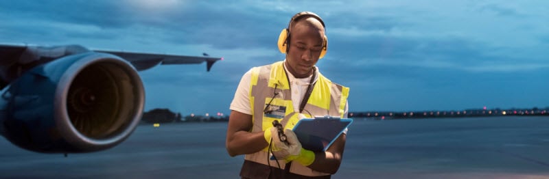 Airport ground crew worker with clipboard under airplane on tarmac